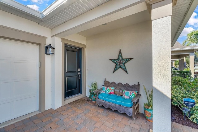 entrance to property with a garage and stucco siding