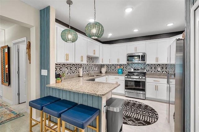 kitchen with decorative backsplash, a peninsula, stainless steel appliances, a kitchen bar, and white cabinetry