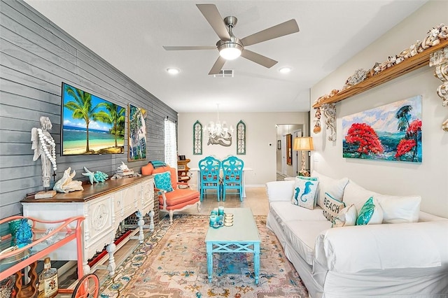 living area with ceiling fan with notable chandelier, recessed lighting, visible vents, and wooden walls