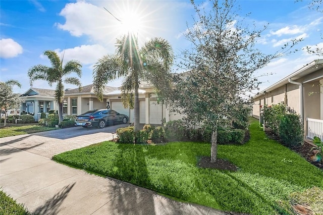 view of front of home with a garage, stucco siding, decorative driveway, and a front yard