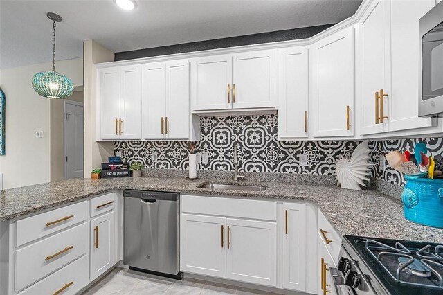 kitchen featuring stainless steel appliances, a sink, white cabinets, light stone countertops, and tasteful backsplash