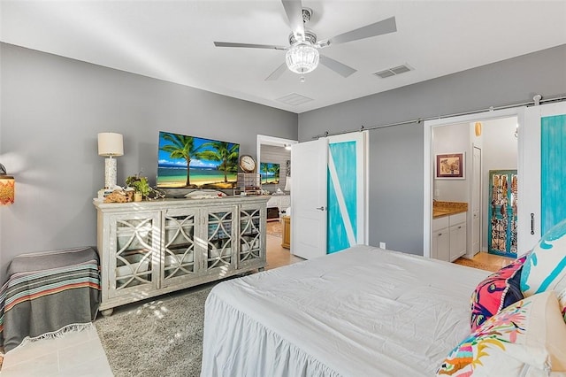 bedroom featuring a barn door, visible vents, a ceiling fan, and ensuite bathroom