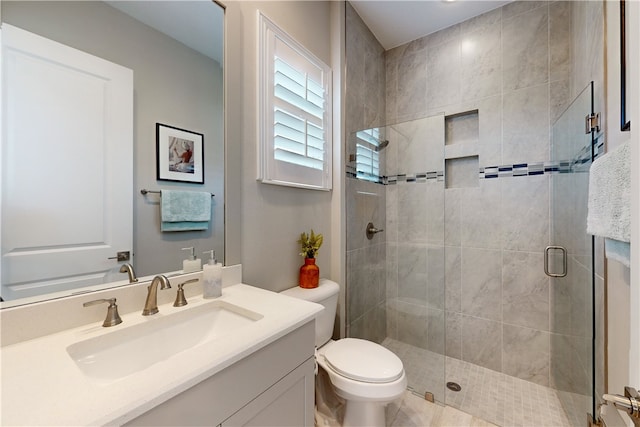 bathroom featuring toilet, vanity, and a shower with shower door