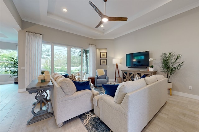 living room with ceiling fan, a raised ceiling, and crown molding