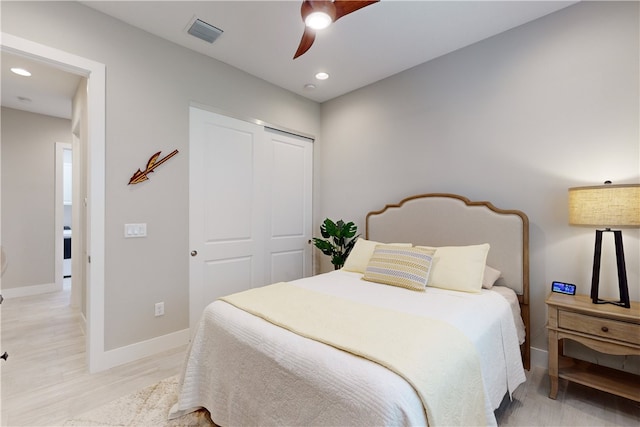 bedroom featuring light hardwood / wood-style floors, ceiling fan, and a closet