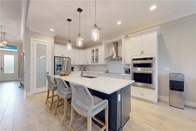 kitchen with white cabinetry, wall chimney range hood, sink, and stainless steel appliances