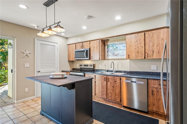 kitchen featuring light tile patterned flooring, sink, decorative light fixtures, appliances with stainless steel finishes, and a kitchen island