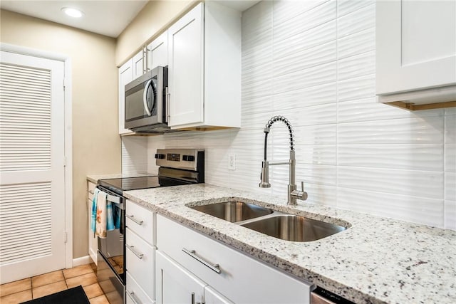 4019 Silver Palm Dr Unit 8, Vero Beach, FL 32963 - kitchen featuring light stone counters, stainless steel appliances, a sink, tasteful backsplash, and white cabinetry