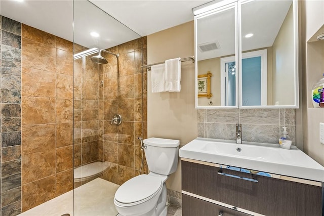 bathroom with vanity, toilet, and a tile shower