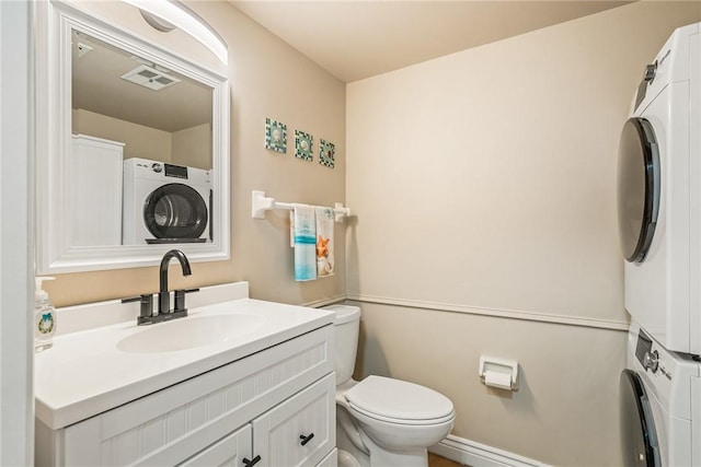 bathroom featuring vanity, toilet, and stacked washer / dryer