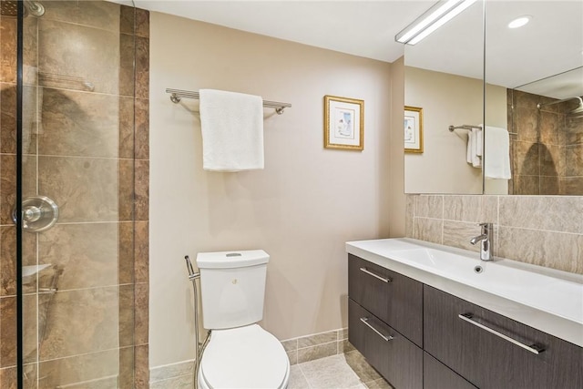 bathroom with tile patterned floors, toilet, a tile shower, vanity, and decorative backsplash