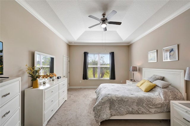 bedroom with ceiling fan, ornamental molding, light carpet, and a tray ceiling