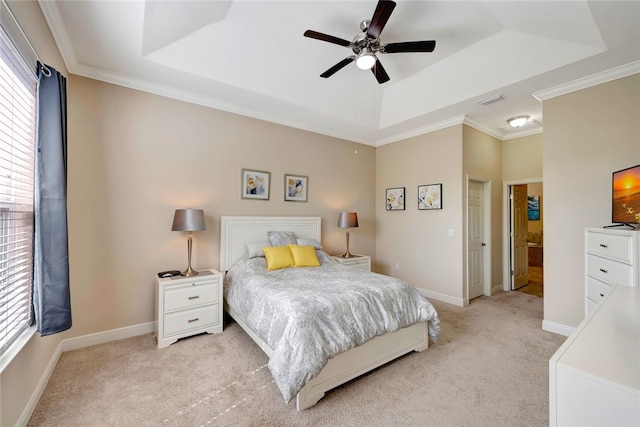 bedroom featuring ceiling fan, ensuite bathroom, light carpet, and a tray ceiling