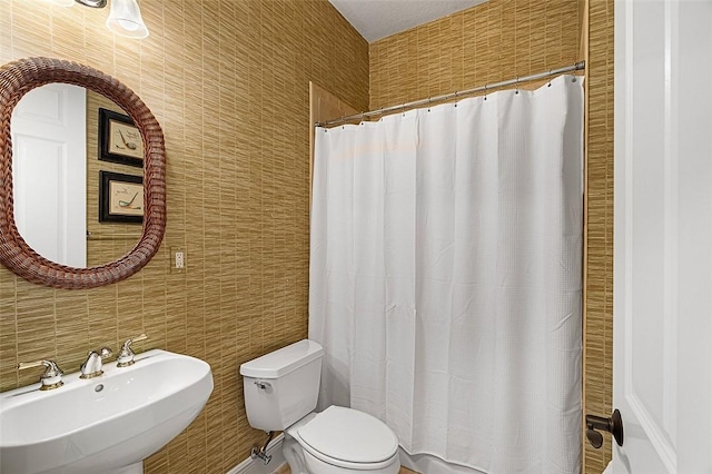 bathroom with toilet, a shower with curtain, a sink, and tile walls