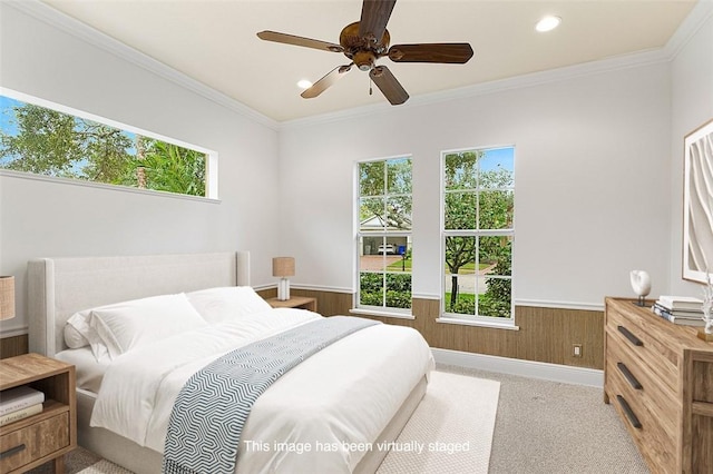 carpeted bedroom featuring ceiling fan, wood walls, ornamental molding, and multiple windows