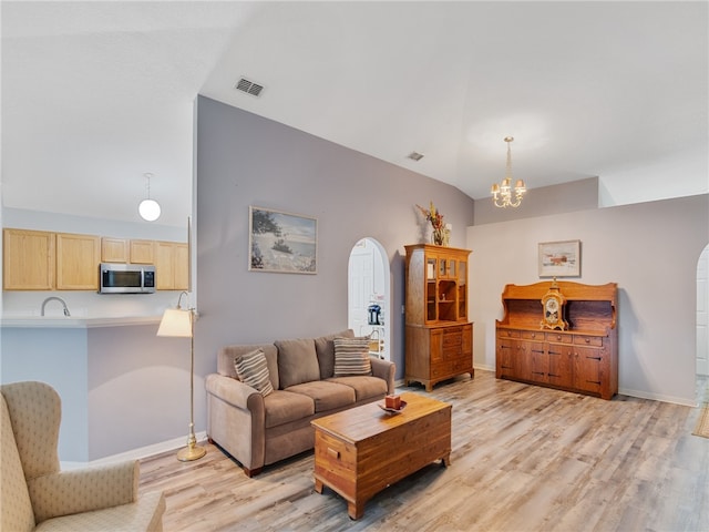 2540 12th Sq SW, Vero Beach, FL 32968 - living room featuring light wood-type flooring, a chandelier, arched walkways, and vaulted ceiling