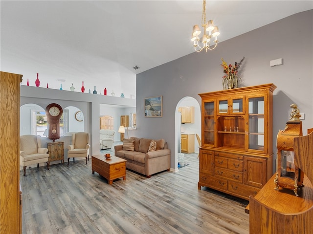 2540 12th Sq SW, Vero Beach, FL 32968 - living room with arched walkways, light wood-style floors, a high ceiling, and a chandelier