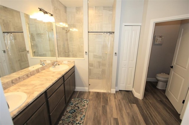 bathroom featuring a shower, vanity, wood-type flooring, and toilet