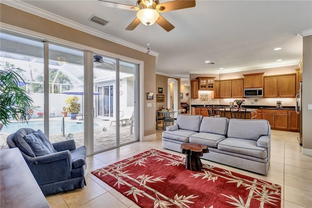 tiled living room with ceiling fan and crown molding