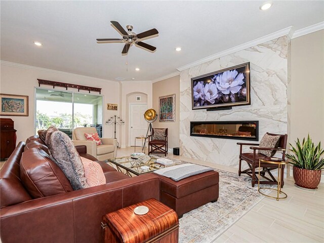 living room featuring ceiling fan, crown molding, and a fireplace