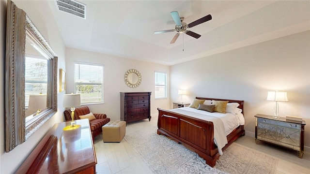 bedroom featuring a tray ceiling, visible vents, and ceiling fan