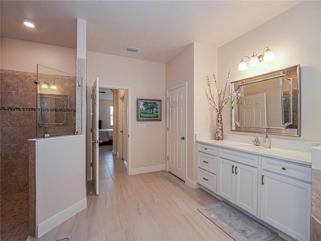 bathroom featuring a tile shower and vanity