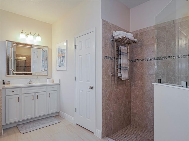 bathroom with a tile shower, vanity, and tile patterned flooring