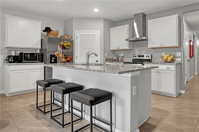 kitchen with wall chimney range hood, white cabinets, and appliances with stainless steel finishes