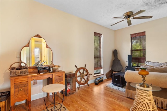 home office with light wood-style flooring, baseboards, ceiling fan, and a textured ceiling