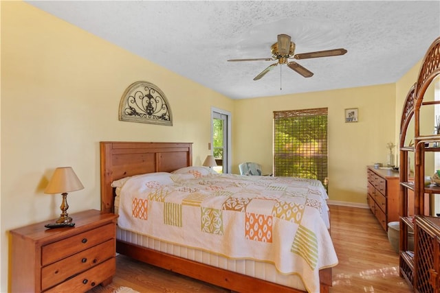 bedroom with a textured ceiling, a ceiling fan, light wood-style flooring, and baseboards