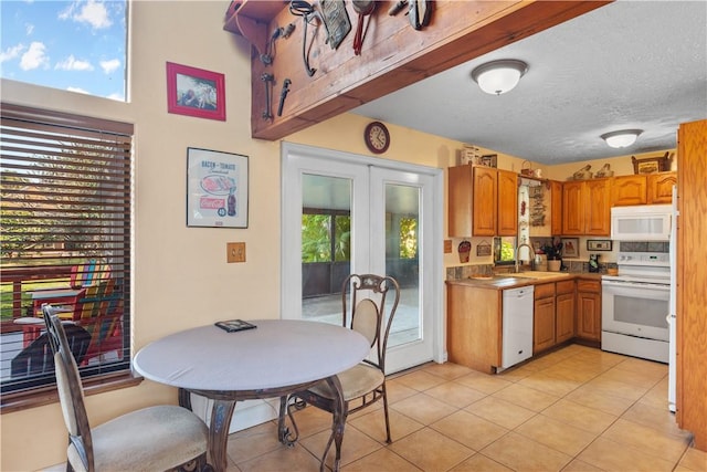 kitchen featuring white appliances, a sink, light countertops, french doors, and brown cabinetry