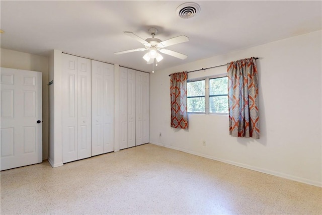 unfurnished bedroom featuring ceiling fan and multiple closets