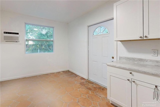 interior space with a wall unit AC, light tile patterned floors, and a wealth of natural light