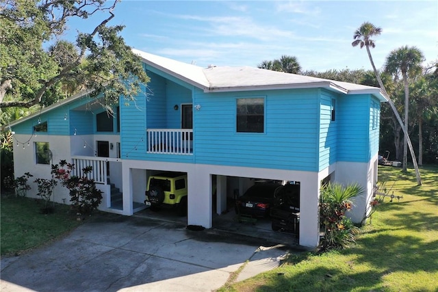 back of house with a carport, a balcony, and a lawn