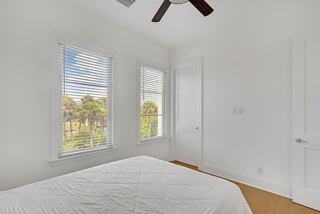 bedroom with multiple windows, wood-type flooring, and ceiling fan