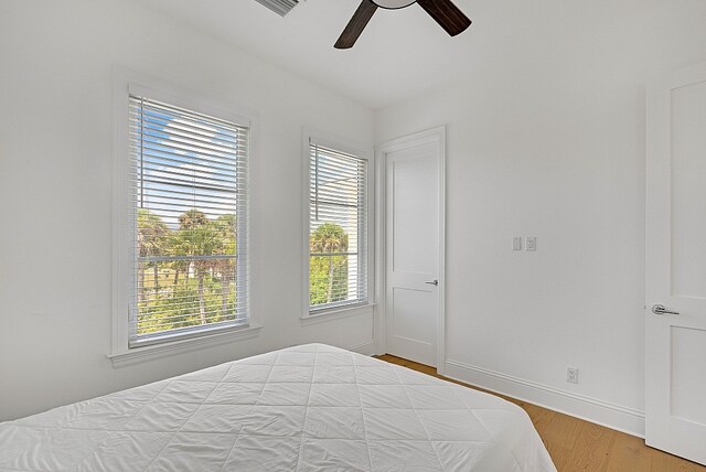 bedroom with multiple windows, wood-type flooring, and ceiling fan