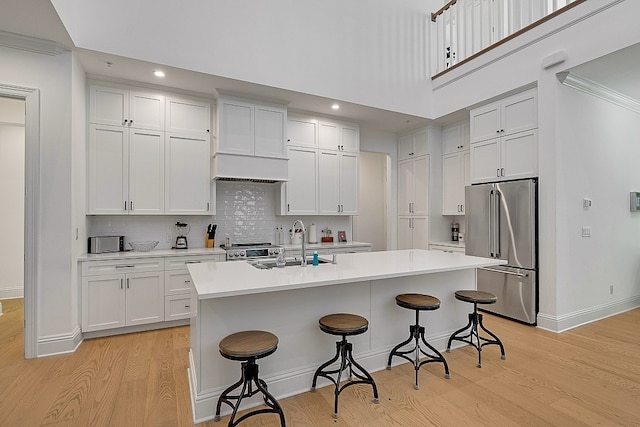 kitchen with stainless steel appliances, white cabinets, an island with sink, and a breakfast bar