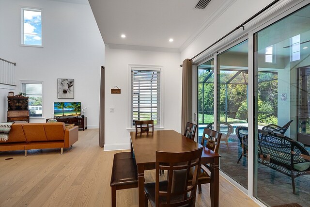 dining space with light hardwood / wood-style floors, a high ceiling, and crown molding