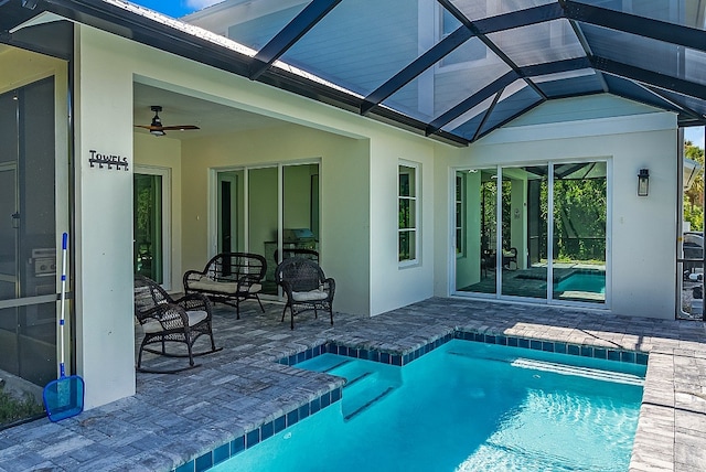 view of pool featuring glass enclosure, a patio, and ceiling fan