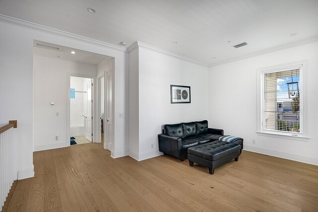 living area featuring light wood-type flooring and crown molding