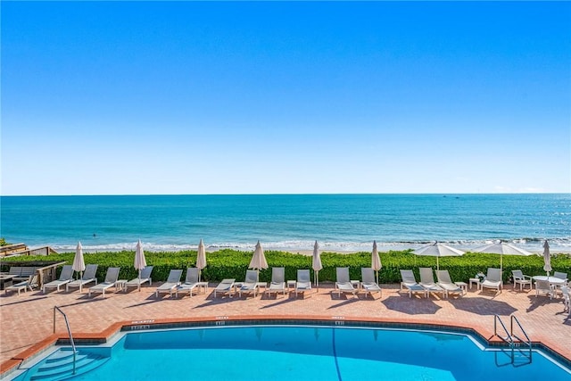 view of pool with a water view, a beach view, and a patio