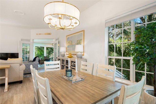 dining space with light hardwood / wood-style floors, an inviting chandelier, and a healthy amount of sunlight