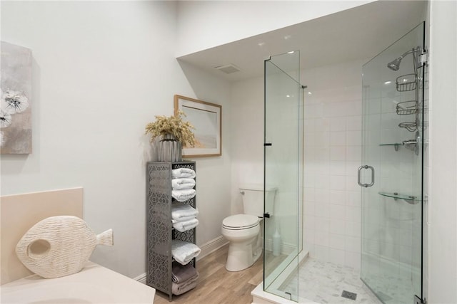 bathroom with toilet, a shower with door, and hardwood / wood-style flooring