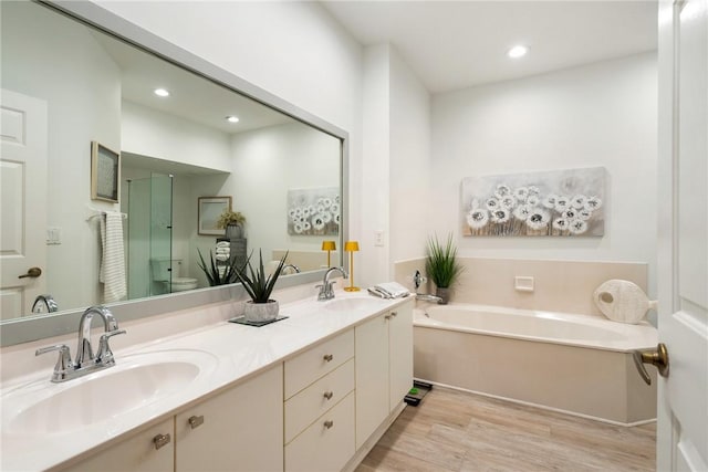 bathroom with a bath, vanity, hardwood / wood-style flooring, and toilet