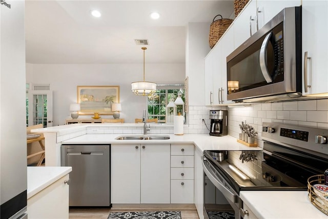 kitchen with appliances with stainless steel finishes, white cabinetry, pendant lighting, and sink