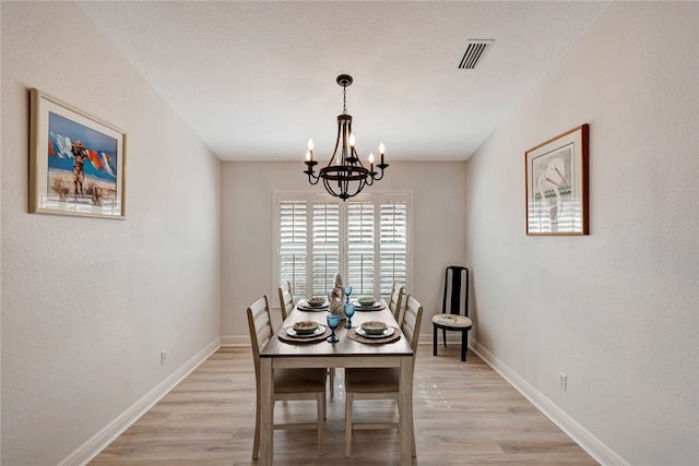 dining space featuring light hardwood / wood-style flooring and an inviting chandelier