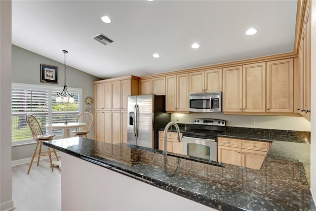 kitchen with stainless steel appliances, dark stone counters, pendant lighting, an inviting chandelier, and lofted ceiling