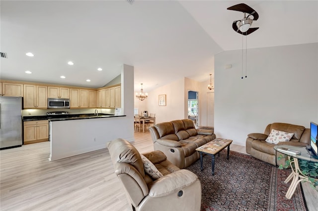 living room featuring an inviting chandelier, sink, light hardwood / wood-style flooring, and vaulted ceiling