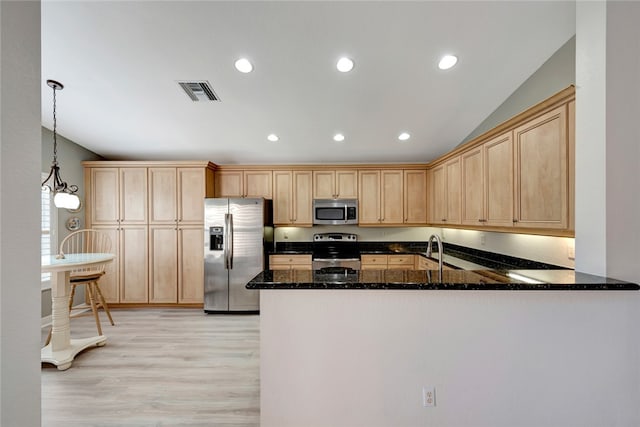 kitchen with stainless steel appliances, kitchen peninsula, dark stone counters, decorative light fixtures, and light wood-type flooring