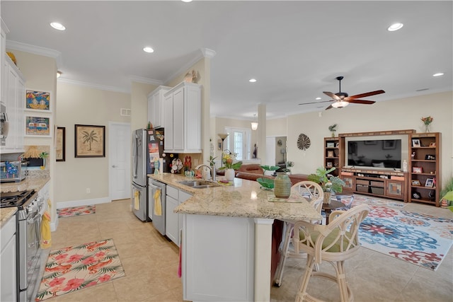 kitchen featuring sink, appliances with stainless steel finishes, ornamental molding, a kitchen breakfast bar, and white cabinets